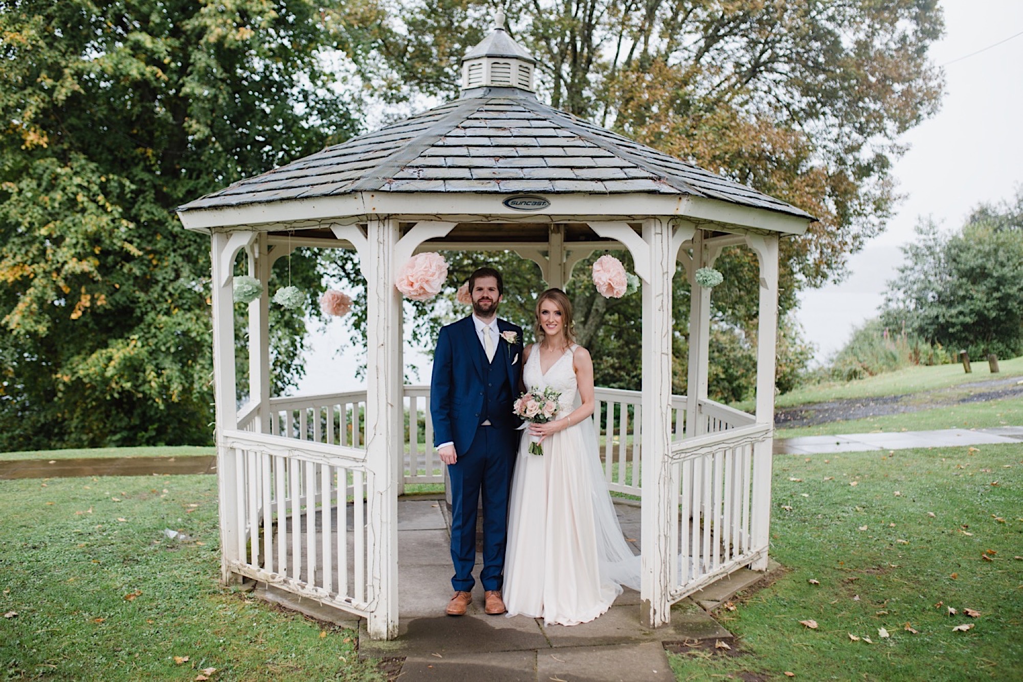 birde and groom rainy wedding day under pergola