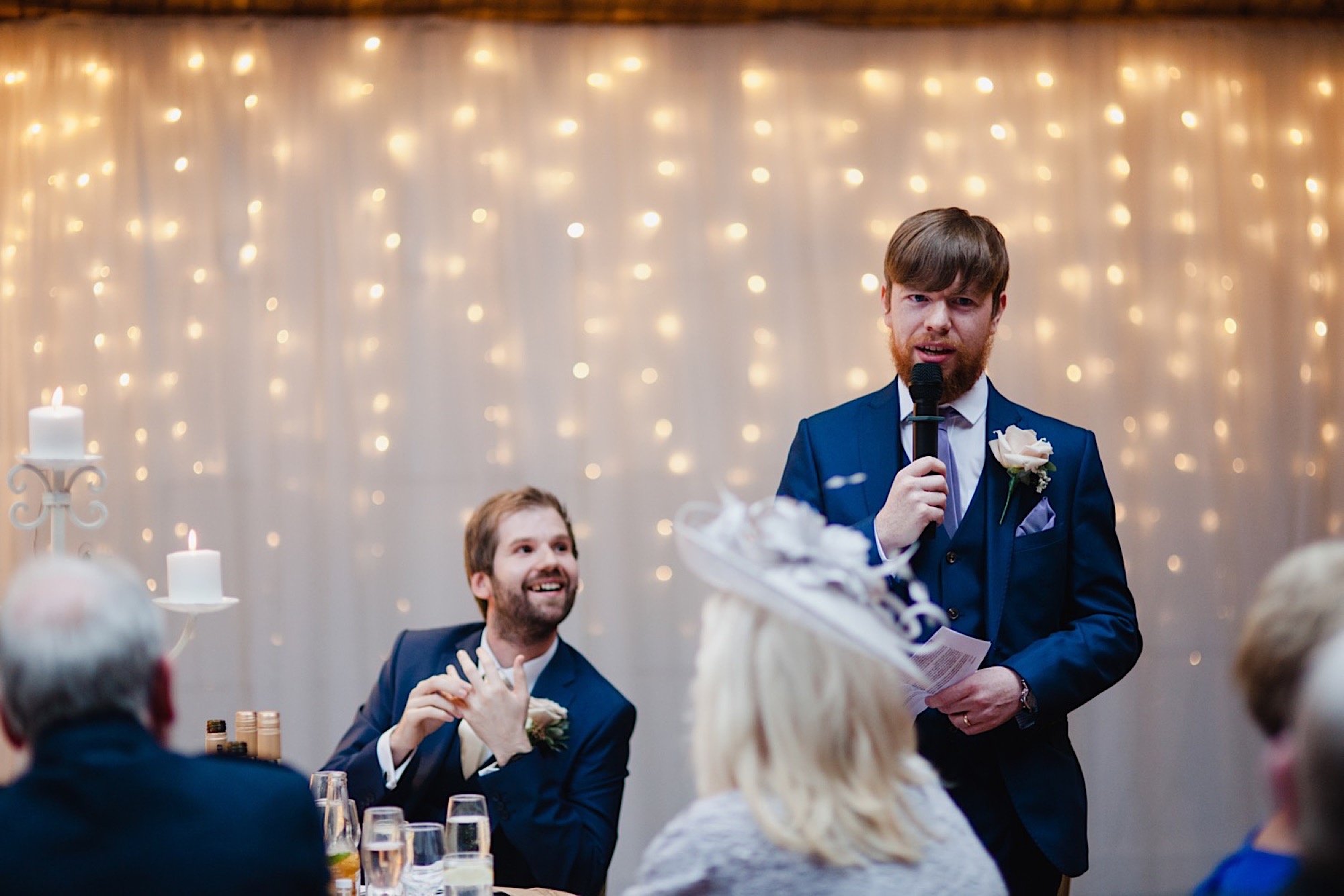 best man wedding speech infront of a fairy light curtain