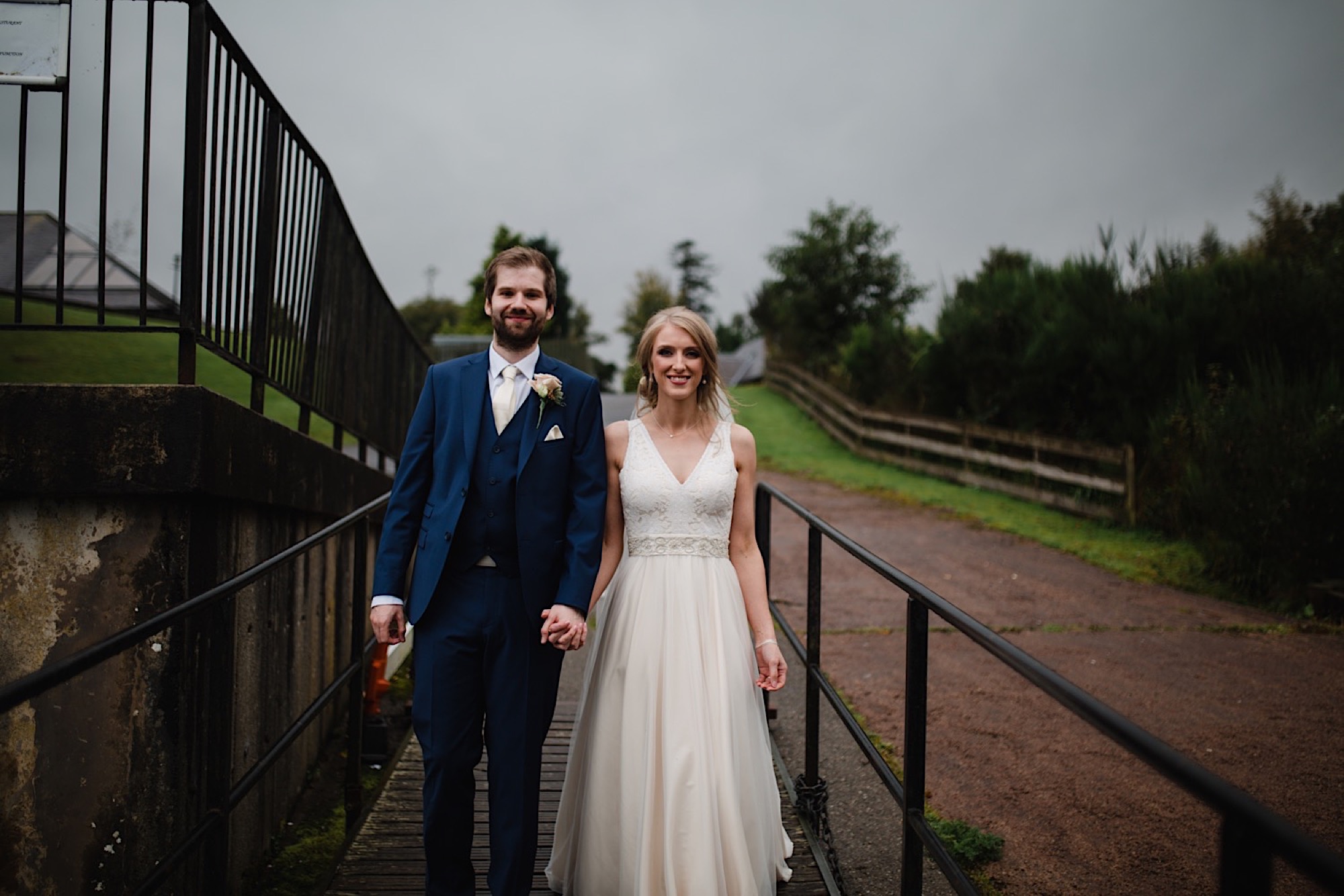 bride and groom on the banks of loch lomand with a dark and moody sky as the rain stops