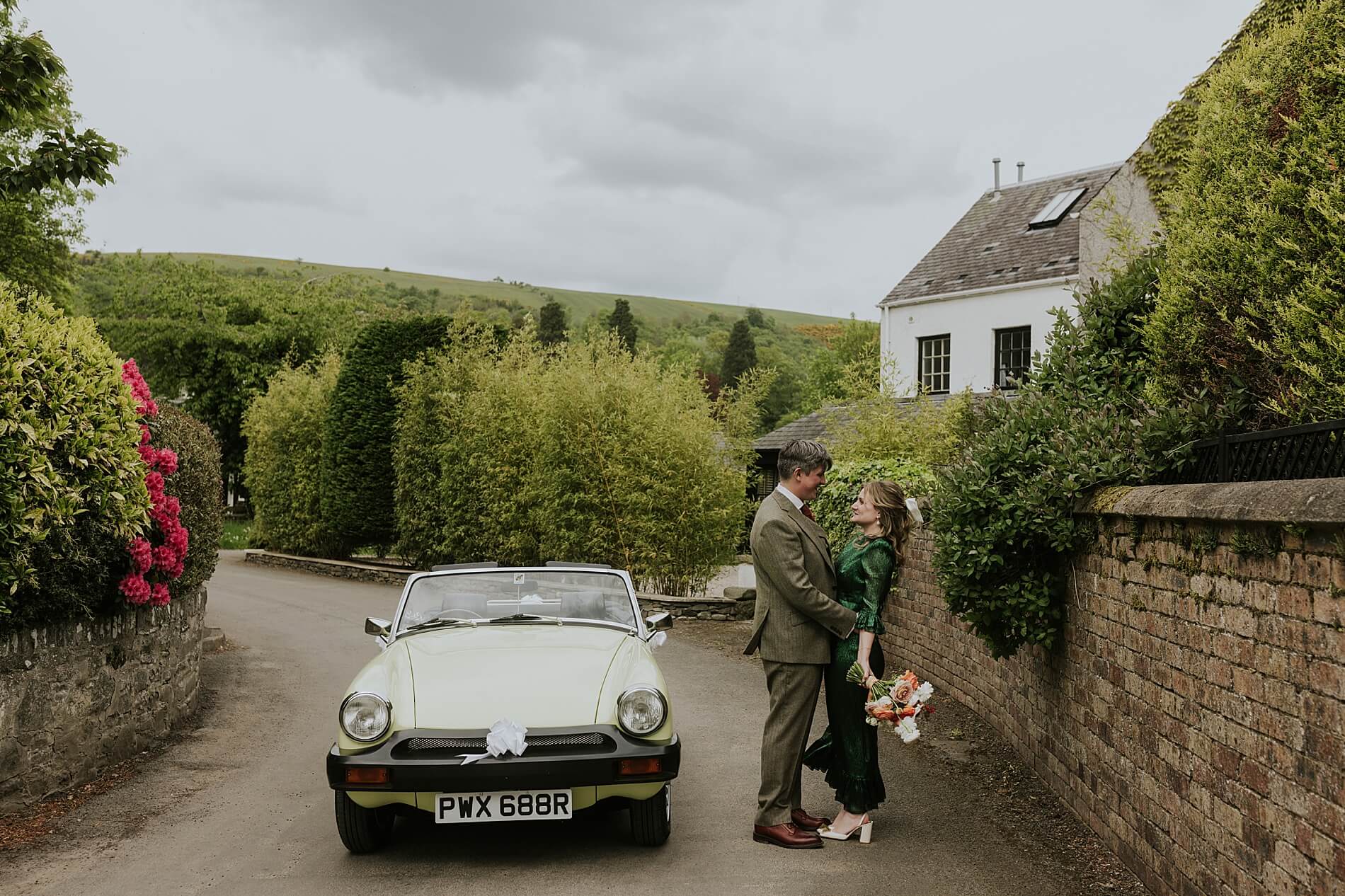 couple pose with classic MG midget wedding car